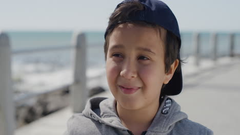 Porträt-Eines-Jungen-Hispanischen-Jungen,-Der-Glücklich-Lächelt-Und-Den-Sommertag-Am-Strand-Mit-Hut-Genießt