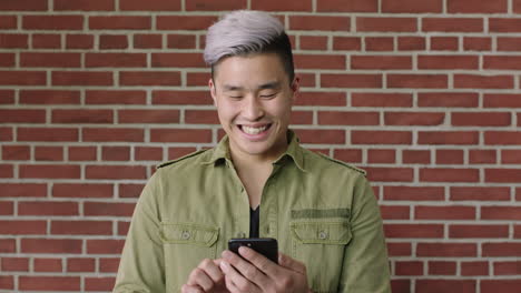 Porträt-Eines-Jungen-Asiatischen-Mannes,-Der-Sein-Smartphone-Lächelt-Und-SMS-Schreibt-Und-In-Sozialen-Medien-Surft