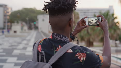Porträt-Eines-Jungen-Afroamerikanischen-Mannes,-Der-Mit-Dem-Smartphone-Fotos-Macht-Und-Das-Fotografieren-Des-Urlaubsziels-Mit-Der-Zeitlupe-Der-Handykamera-Technologie-Genießt