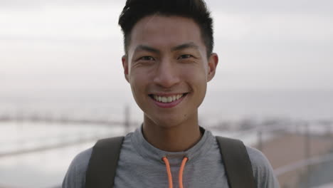 Nahaufnahme-Eines-Porträts-Eines-Charmanten-Jungen-Asiatischen-Mannes,-Der-Fröhlich-Und-Optimistisch-Am-Bewölkten-Meer-Lächelt
