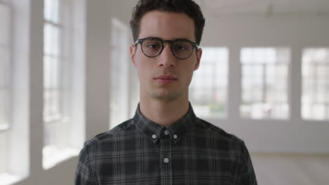 close-up-portrait-of-attractive-young-hipster-man-looking-serious-at-camera-in-new-apartment-wearing-glasses
