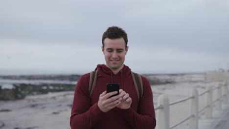 close-up-portrait-of-caucasian-man-texting-using-phone-smiling-on-beach