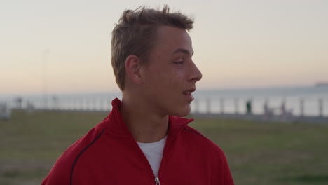 portrait-young-teenage-boy-looking-around-smiling-enjoying-relaxed-day-on-seaside-park-at-sunset-distracted-caucasian-kid-slow-motion