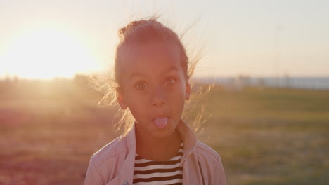 portrait-young-little-mixed-race-girl-making-faces-enjoying-summer-vacation-on-beautiful-park-at-sunset-real-people-series