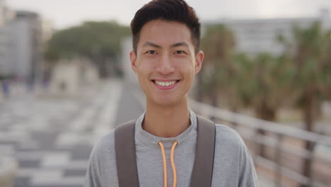 portrait-happy-young-asian-man-tourist-smiling-enjoying-summer-vacation-independent-teenage-male-looking-cheerful-on-urban-waterfront-at-sunset-real-people-series