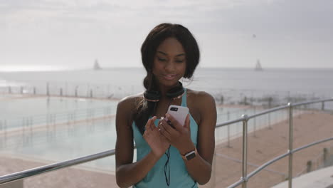 Porträt-Einer-Athletischen-Afroamerikanischen-Frau,-Die-Am-Schwimmbad-Am-Meer-Telefoniert-Und-SMS-Schreibt