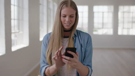slow-motion-portrait-of-beautiful-young-blonde-woman-in-new-apartment-room-texting-browsing-using-smartphone-mobile-technology-happy-excited