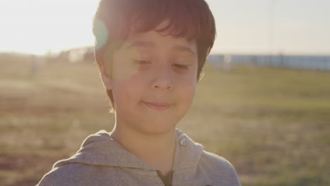 close-up-portrait-cute-hispanic-boy-smiling-happy-looking-calm-enjoying-relaxed-summer-day-on-seaside-park-at-sunset-carefree-childhood