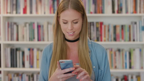 Porträt-Einer-Schönen-Blonden-Frau,-Die-Ihr-Smartphone-Nutzt,-Um-SMS-Zu-Schreiben-Und-Online-Nachrichten-Zu-Durchsuchen-Und-Mobile-Kommunikationstechnologie-Im-Bücherregal-Der-Bibliothek-Im-Hintergrund-Zu-Genießen