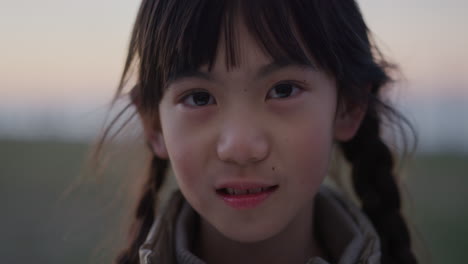 Nahaufnahme-Eines-Porträts-Eines-Kleinen-Asiatischen-Mädchens,-Das-Glücklich-Lächelt-Und-Die-Sommerferien-Im-Sonnenuntergang-Am-Meer-Im-Park-Mit-Echten-Menschen-Genießt