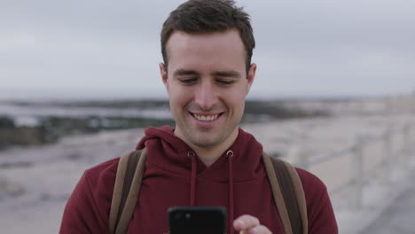 close-up-portrait-of-charming-caucasian-man-texting-using-phone-on-beach
