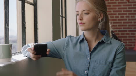 beautiful-blonde-woman-using-smartphone-drinking-coffee-at-home-enjoying-texting-browsing-social-media-looking-out-window-thinking-contemplative
