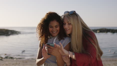 beautiful-woman-friends-smiling-laughing-using-phone-looking-browsing-photos-on-pleasant-sunny-beach-day