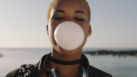 close-up-portrait-of--young-happy-african-american-woman-blowing-bubblegum-having-fun-on-beach