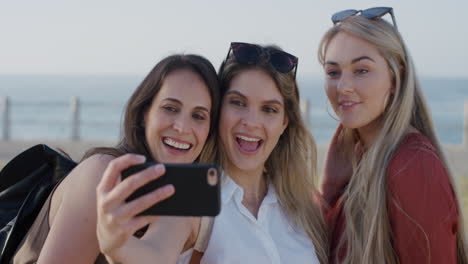 Porträt-Einer-Gruppe-Schöner-Kauasischer-Freundinnen,-Die-Mit-Dem-Smartphone-Ein-Selfie-Foto-Machen-Und-Dabei-Lächeln-Und-Das-Abhängen-An-Einem-Warmen,-Sonnigen-Sommerurlaubstreffen-Am-Meer-Genießen