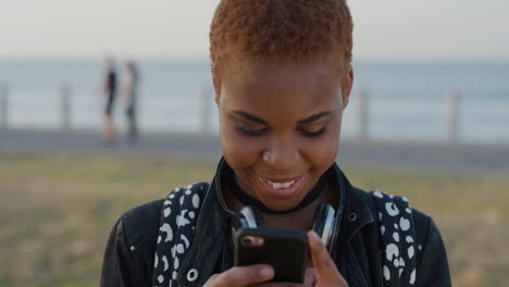 Porträt-Einer-Stilvollen-Afroamerikanischen-Frau,-Die-Ihr-Smartphone-Benutzt-Und-Lächelnd-Ein-Selfie-Foto-Macht,-Das-Den-Erfahrungsaustausch-Mit-Mobiler-Kameratechnologie-Am-Meer-Im-Hintergrund-Genießt