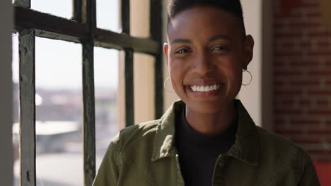 portrait-beautiful-african-american-woman-looking-out-window-smiling-at-camera-enjoying-positive-lifestyle-relaxing-at-home-trendy-black-female-in-new-york-apartment