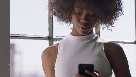 stylish-woman-using-smartphone-at-home-browsing-messages-enjoying-relaxed-lifestyle-looking-out-window-planning-ahead-black-female-texting-on-mobile-phone