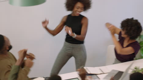 successful-black-business-people-celebrating-success-enjoying-corporate-victory-presentation-team-leader-woman-excited-dancing-funny-in-boardroom-meeting-top-view
