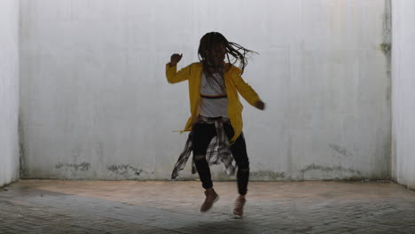 Mujer-Bailando-Joven-Bailarina-Callejera-De-Raza-Mixta-Realizando-Movimientos-De-Hip-Hop-De-Estilo-Libre-Disfrutando-De-La-Expresión-De-Danza-Moderna-Practicando-En-Un-Almacén-Sucio-Con-Chaqueta-Amarilla