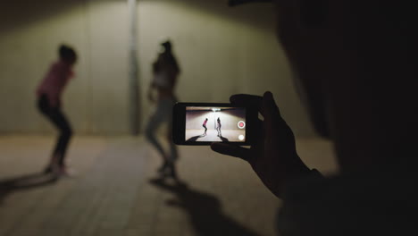 Tanzende-Frau,-Fröhliche-Hip-Hop-Tänzerin,-Mädchen-Tanzen-Unter-Straßenlaterne,-Freund-Mit-Smartphone,-Der-Videos-Aufnimmt-Und-Es-Genießt,-Sie-Nachts-In-Den-Sozialen-Medien-In-Der-Stadt-Zu-Teilen