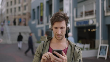 portrait-of-young-attractive-caucasian-man-in-busy-urban-street-wearing-headphones-listening-to-music-enjoying-lifestyle