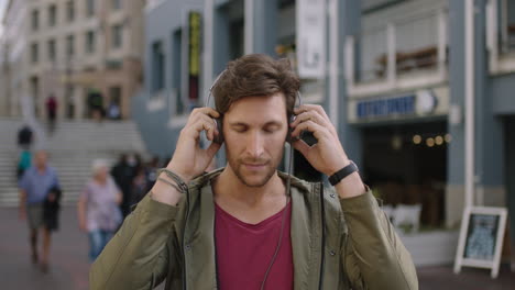 portrait-of-young-attractive-caucasian-man-in-busy-urban-street-wearing-headphones-listening-to-music-enjoying-lifestyle