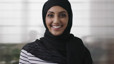 Porträt-Einer-Professionellen-Jungen-Muslimischen-Geschäftsfrau,-Die-Lachend-In-Die-Kamera-Blickt-Und-Ein-Traditionelles-Kopftuch-Im-Bürohintergrund-Trägt