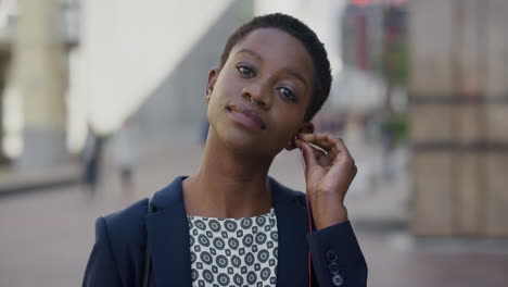 Retrato-Hermosa-Joven-Mujer-De-Negocios-Afroamericana-Se-Pone-Auriculares-Escuchando-Música-Sonriendo-Disfrutando-De-Un-Estilo-De-Vida-Urbano-Relajado-En-El-Entretenimiento-Portátil-De-La-Ciudad