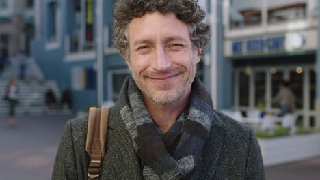 slow-motion-portrait-of-attractive-mature-caucasian-man-smiling-confident-at-camera-wearing-scarf-in-urban-background