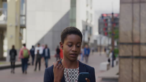 Retrato-Profesional-Afroamericana-Mujer-De-Negocios-Usando-Un-Teléfono-Inteligente-Usando-Auriculares-Navegando-En-Línea-Revisando-Mensajes-Escuchando-Música-En-La-Ciudad