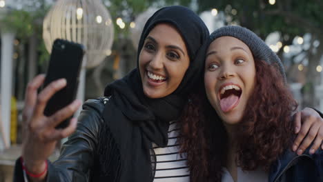 portrait-young-multi-ethnic-women-friends-using-smartphone-taking-selfie-photo-making-faces-enjoying-relaxed-fun-girlfriends-hang-out-in-city-slow-motion