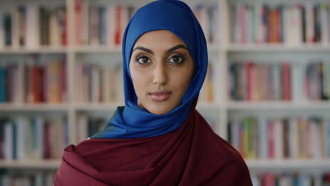 Porträt-Einer-Schönen-Jungen-Muslimischen-Frau,-Die-Ruhig-Und-Unabhängig-Aussieht-Und-Hijab-Im-Bücherregal-Hintergrund-In-Zeitlupe-Trägt