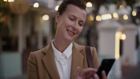 portrait-stylish-senior-business-woman-using-smartphone-texting-browsing-online-checking-messages-professional-urban-female-entrepreneur-sending-email-on-mobile-phone-in-city-evening