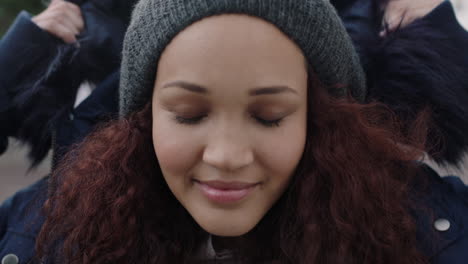 close-up-portrait-of-young-beautiful-mixed-race-woman-with-frizzy-hair-smiling-enjoying-wearing-beanie-fur-coat-looking-at-camera