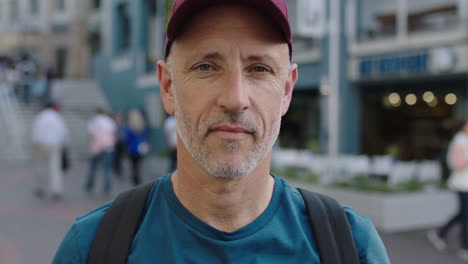 close-up-portrait-of-mature-attractive-caucasian-tourist-man-wearing-hat-looking-at-camera-pensive-city-background