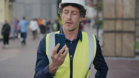 portrait-mature-construction-engineer-man-using-smartphone-browsing-working-on-site-wearing-safety-helmet-reflective-clothing-in-city-slow-motion