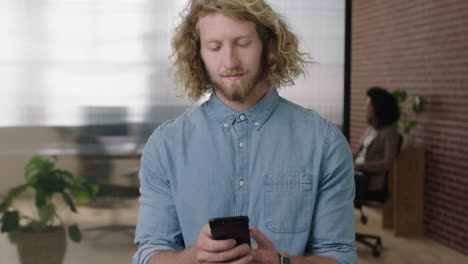 portrait-of-young-charming-blonde-man--texting-browsing-using-smartphone-social-media-app-checking-messages-in-office-workspace