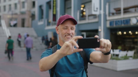 portrait-of-mature-attractive-caucasian-tourist-man-wearing-hat-using-smartphone-taking-photo-sightseeing