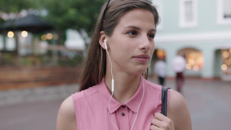 slow-motion-portrait-of-young-beautiful-woman-wearing-earphones-listening-to-music-checking-wrist-watch-smiling-cheerful-at-camera-evening-urban-background