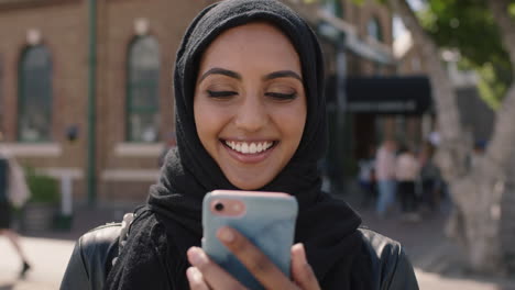 Retrato-De-Una-Joven-Y-Bonita-Mujer-Musulmana-Viendo-Videos-En-Un-Teléfono-Inteligente-Riendo-Alegremente