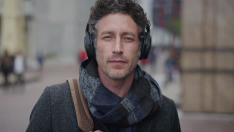portrait-attractive-mature-businessman-wearing-headphones-listening-to-music-enjoying-relaxed-urban-commuting-lifestyle-on-city-street-slow-motion