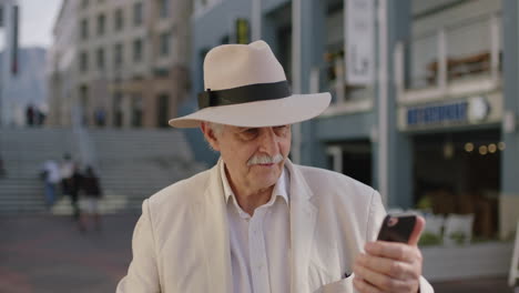 Porträt-Eines-Stilvollen-älteren-Mannes,-Der-Mit-Smartphone-Video-Chat-Technologie-Winkt-Und-Mobile-Kommunikation-In-Einer-Geschäftigen-Stadt-Genießt
