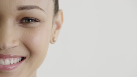 Nahaufnahme-Einer-Schönen-Hispanischen-Frau-Mit-Halbem-Gesicht,-Die-Glücklich-Lächelt-Und-Ohrringe,-Make-up-Kosmetik-Auf-Weißem-Hintergrund-Trägt