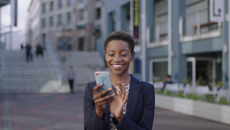 Porträt-Einer-Unabhängigen-Afroamerikanischen-Geschäftsfrau,-Die-Glücklich-Lächelt-Und-Smartphone-SMS-Beim-Surfen-In-Der-Stadt-Nutzt