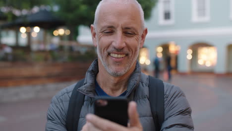 portrait-of-mature-attractive-caucasian-tourist-man-using-smartphone-app-texting-browsing-enjoying-evening-urban-travel