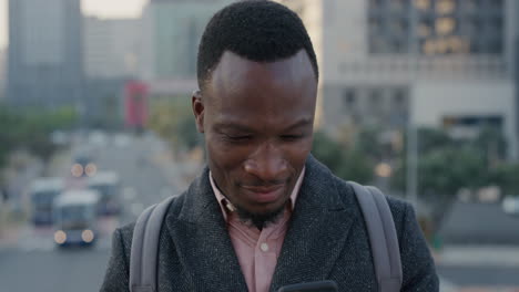 portrait-professional-african-american-businessman-using-smartphone-enjoying-browsing-online-messages-texting-on-mobile-phone-in-city-at-sunset-slow-motion