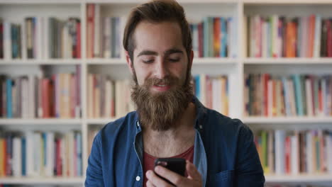 portrait-attractive-bearded-hipster-man-using-smartphone-browsing-messages-enjoying-texting-on-mobile-phone-in-library-young-male-student-researching-online-slow-motion