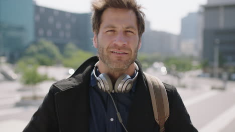 portrait-of-handsome-young-caucasian-man-in-sunny-urban-city-listening-to-music-removes-headphones-looking-at-camera-enjoying-relaxed-lifestyle