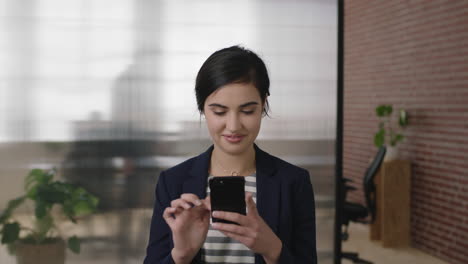 portrait-of-beautiful-young-business-woman-using-smartphone-mobile-technology-texting-browsing-in-office-workspace